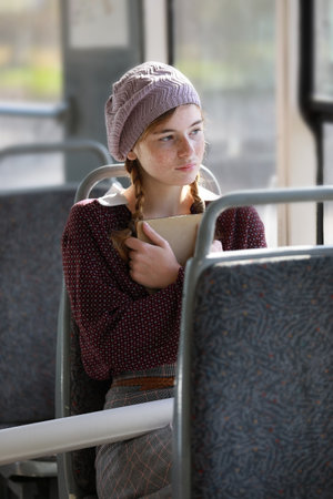 Likable girl in retro style clothes rides in an empty city tram on a summer dayの写真素材