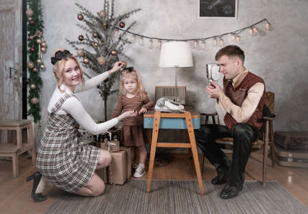Dad shoots a vintage film camera of a child at home on Christmas day. Retro style family in a Christmas backgroundの写真素材