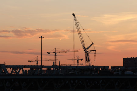 Construction cranes working on the construction of multi storey residential buildings at sunset....