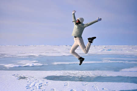 Cheerful girl having fun on the snow covered surface of a frozen Lake Baikal, Russia. Winter holidays, ice travelの写真素材