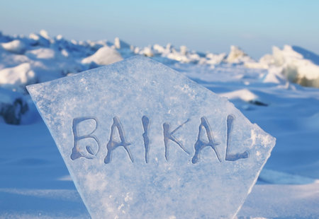 Large transparent ice floe with the inscription Baikal on the background of hummocks on Lake Baikal...