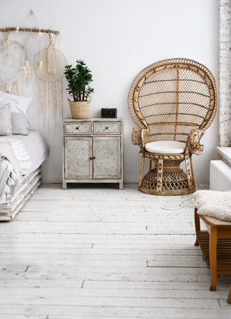 Bedside table and a chair next to the bed in a modern bedroom flooded with daylightの写真素材