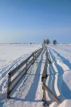 Winter landscape with a bridge over a frozen lake on a clear sunny day. Winter holidays, ice travelの写真素材