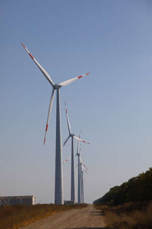 Row of windmills spinning at sunrise against a clear blue skyの写真素材