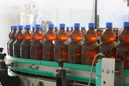 Plenty of plastic bottles filled with beer are moving along the conveyor belt