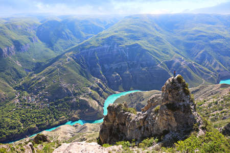 Tourist girl on the top of a cliff against the background of the Sulak canyon surrounded by mountains. Natural landmark Sulak Canyon in Dagestan, Russiaの写真素材