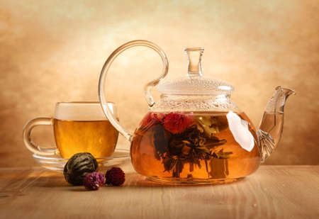 Glass tea teapot with a blooming tea flower stands on the table indoorsの写真素材