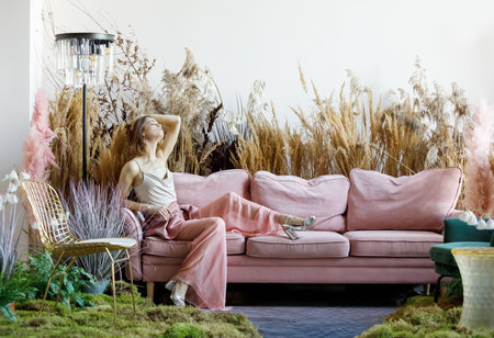Fantasy concept with a nice woman posing in a room in the middle of tall grass with the floor flooded with waterの写真素材