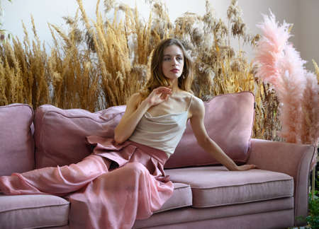 Pleasant woman sitting on a sofa in a room in the middle of tall grassの写真素材