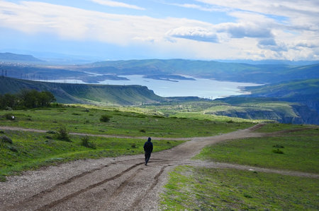 Mature man walking on dirt road against cloudy sky
