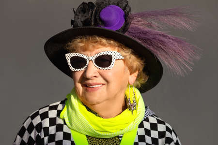 Portrait of an senior woman in sunglasses and bright clothes on an autumn sunny dayの写真素材