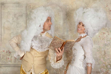 Cute couple in Baroque style clothes reading a book indoorsの写真素材