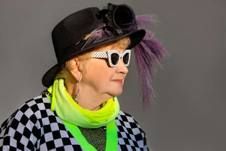 Portrait of a senior woman in sunglasses and black hat outdoorsの写真素材