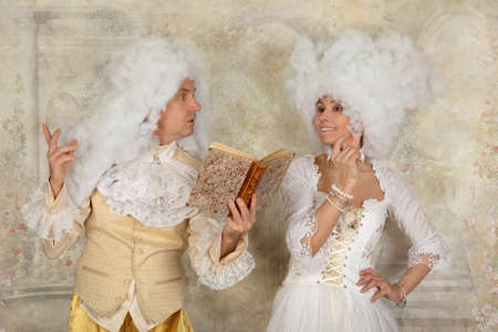 Cute couple in Baroque style clothes reading a poetry indoorsの写真素材