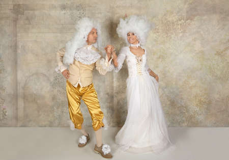 Funny couple in white wigs and Baroque style clothes dancing in the studioの写真素材