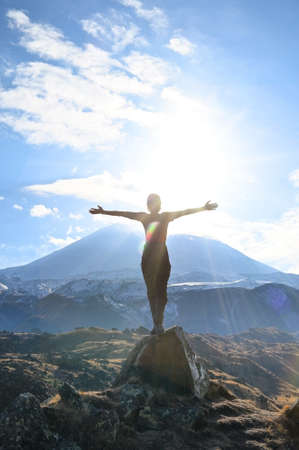 Hiker young woman enjoys nature on top of a mountain against backdrop of sunshine. Discovery travel destination conceptの写真素材