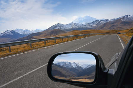 The Caucasus Mountains are displayed in the rear view mirror of a car on the way to Mount Elbrus, Russiaの写真素材