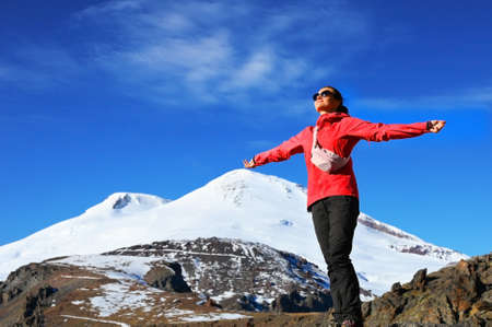 Young female tourist enjoys mountain views by climbing to the top of a mountain in the Elbrus region in Russiaの写真素材