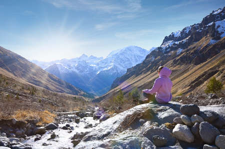 Travel destination concept with young female tourist enjoying a mountain view with the rising sun in the Elbrus mountains in Russiaの写真素材
