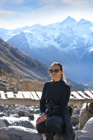 Beautiful young woman tourist posing on the background of Elbrus mountains in Russiaの写真素材