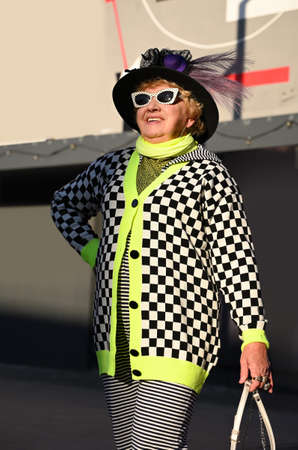 Stylishly dressed elderly woman walks around the streets on a sunny autumn dayの写真素材