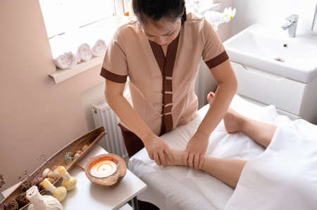 Young woman does a relaxing foot massage in a Vietnamese spa salonの写真素材