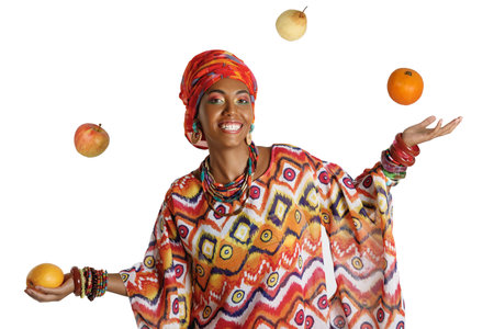 Beauty African woman in traditional clothes juggling fruits in the studio, isolated on a white backgroundの写真素材