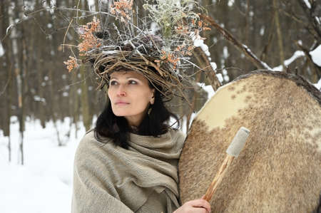 Portrait of a young adult shaman woman during an outdoor music ceremony in a winter forestの写真素材