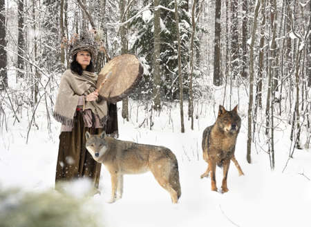 Forest woman performs a shamanic ritual with wild wolves in a winter forestの写真素材