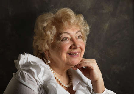 Portrait of a smiling old woman on a black art background  in the studioの写真素材