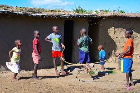 MAASAI MARA NATIONAL RESERVE, KENYA, AFRICA - NOVEMBER 11, 2022: Picture of some maasai children play jumping jacks beside their home in maasai village in Kenya, Africaのeditorial素材