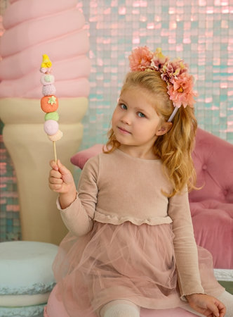 Portrait of a cute little girl with cotton candy in her hand in the studioの写真素材