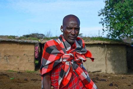 MAASAI MARA NATIONAL RESERVE, KENYA, AFRICA - NOVEMBER 11, 2022: Maasai village with maasai tribe. Portrait of a maasai man  in traditional clothing against the blue sky in maasai village in Kenya, Africaのeditorial素材