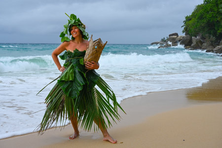 woman dressed in palm branches on the seashore of a small tropical islandの写真素材
