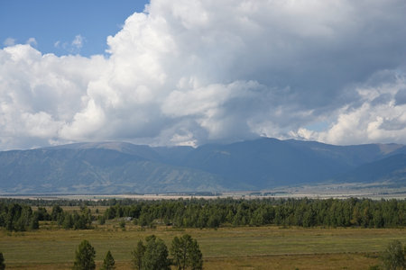 Floating cumulus clouds over the valley and mountains. Natural landscape on a sunny summer dayの写真素材