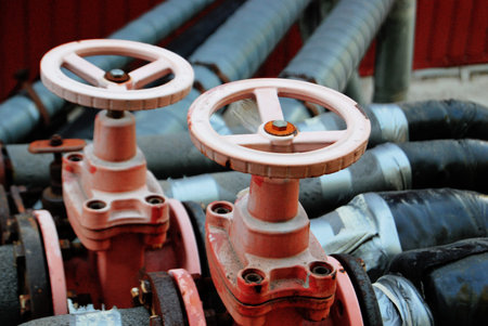Two red valves on black water pipes