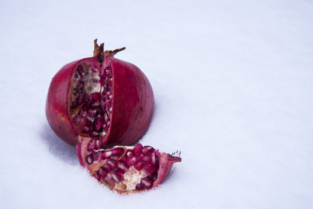 The pomegranate is red, ripe, lying on the snow. Separate lobe.の写真素材