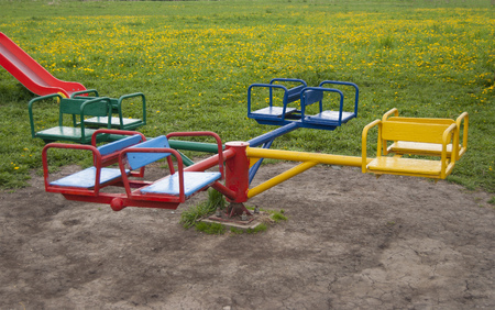 Children's carousel in four places, colorful against a background of green grass with yellow dandelionsの写真素材
