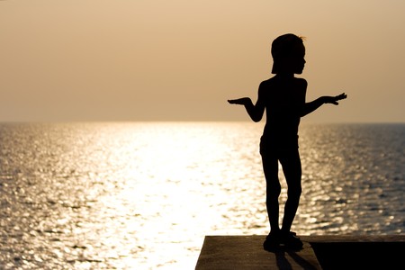A silhouette of a boy dancing at sunsetの写真素材