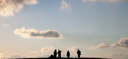 People go to heaven. Silhouettes of four people in the background of sky with clouds at sunsetの写真素材