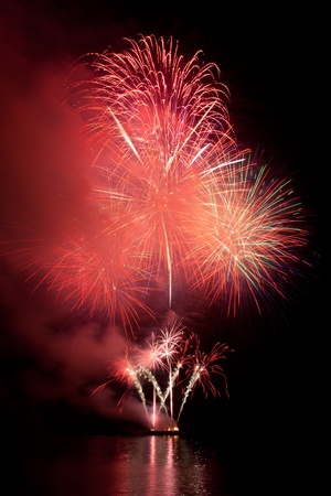 Beautiful fireworks in the night sky with reflection on water の写真素材