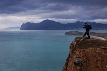 Photographer on the edge of cliff shoots seascape