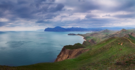 Seacoast with green hills and high mountains の写真素材
