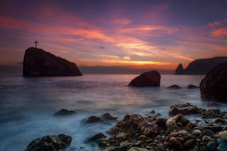 Seascape. Seacoast at sunset and a cross on a rockの写真素材