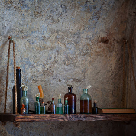 The old pharmacist's bottle with liquids on the shelf against the dilapidated walls の写真素材