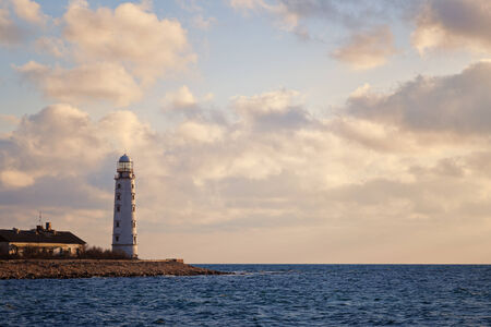 Lighthouse on the coast on the background of sky with cloudsの写真素材