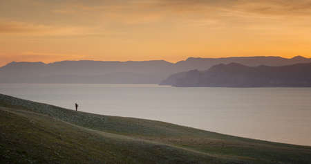 Landscape. Sunset over the mountains and sea with cloudsの写真素材