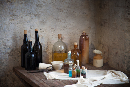 The old pharmacist's bottle with liquids on the shelf against the dilapidated wallsの写真素材