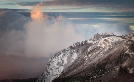 Snowy forest and cliffs on a background of clouds and blue sky. Ai-Petri. Crimea. Russiaの写真素材
