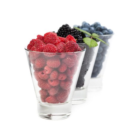 Berry raspberries blackberry blueberries in glass cups isolated on white backgroundの写真素材